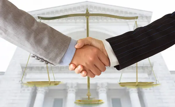 弁護士は 裁判所とのビジネスマンとの握手と バックグラウンドで正義のスケール 法律の概念 ストック写真