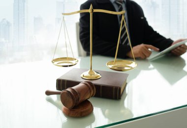 judge hammer, law book and scales of justice on desk with lawyer using digital tablet in law office. legal services concept. clipart