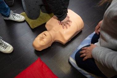 Üç kişi suni teneffüs ve suni teneffüs maniküsüyle ilk yardım ve kalp masajı yapıyor.