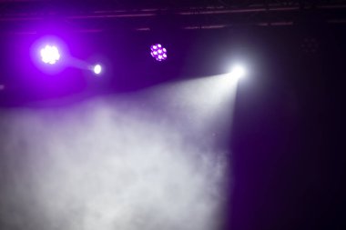 Sahne ışıklandırması. Sahnede renkli ışıkları olan spot ışıkları. Yapay ışıklandırma. Siyah arkaplan ve bulanık.