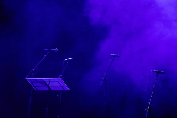 Microphones on a stage before a concert. Dark stage with purple lighting