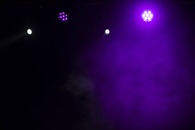 Sahne ışıklandırması. Sahnede renkli ışıkları olan spot ışıkları. Yapay ışıklandırma. Siyah arkaplan ve bulanık.