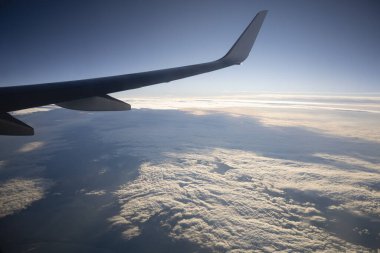 Uçuşun ortasında arka planda bulutlar olan bir uçağın kanat görüntüsü
