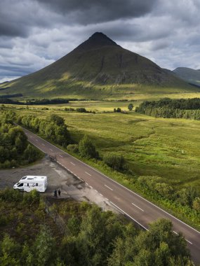 İskoç dağlarındaki Orchy Köprüsü 'nü geçerken turistlerle dolu bir karavan A82 yolunda ilerliyor.