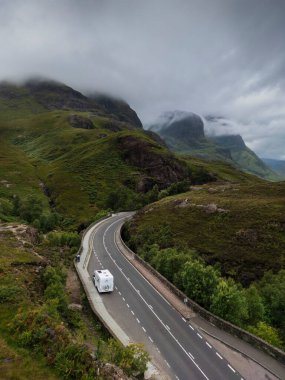 A82 yolunda park etmiş bir karavan Glencoe 'daki Üç Su Buluşması' ndan geçiyor. Glencoe 'nun Üç Kız Kardeş Dağları arkada