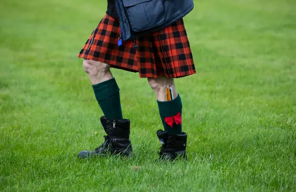 A Scottish Highland Games judge walks around the field wearing a red kilt in the town of Crieff