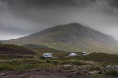 Glencoe dağlarındaki A82 yolunda Glencoe gözcülerinden çarpıcı bir gökyüzü olan motorlu evler ve karavanlar.