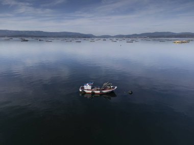 Küçük ahşap bir balıkçı teknesi Arousa nehrinde demirlemiş. Midye çiftçiliği çokgeni