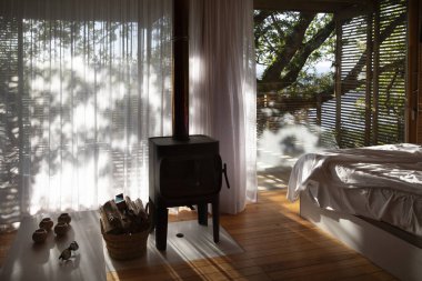 Odun sobası olan bir kulübede gün doğumu ışığı ve büyük bir ağacı olan bir güneş odası.