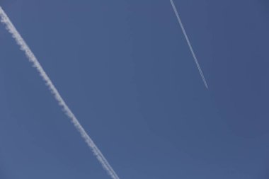 Mavi gökyüzünde beyaz patikaları olan iki uçak