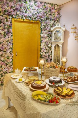 Pastane, ev yapımı tatlılar, pasta ve meyvelerle dolu bir masa. Yapay çiçekler ve güllerle dekorasyon