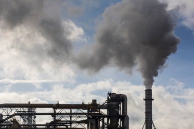 Ahşap işleme fabrikasının bacası. Beyaz bulutlu mavi gökyüzünde beyaz dumanlı baca