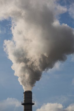 Ahşap işleme fabrikasının bacası. Beyaz bulutlu mavi gökyüzünde beyaz dumanlı baca