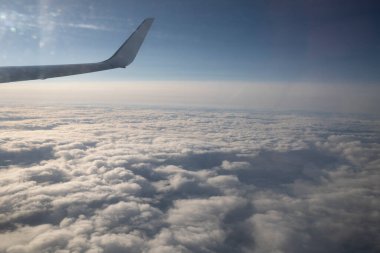 Bulutların manzarası ve pencereden bir uçak kanadı. Uçakla uçmak, uçakla seyahat etmek.