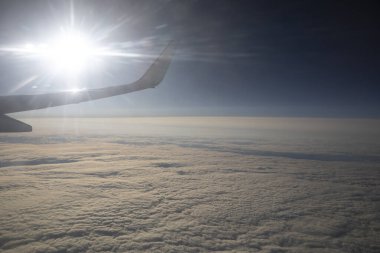 Bulutların manzarası ve pencereden bir uçak kanadı. Uçakla uçmak, uçakla seyahat etmek.