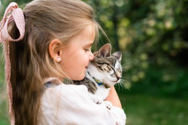 Kollarında kedi yavrusu olan küçük bir kızın portresi.
