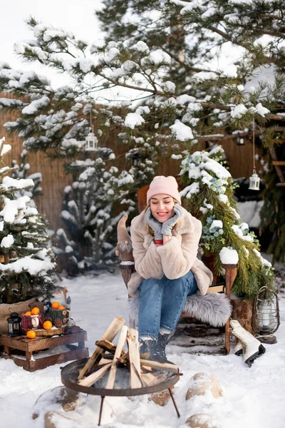Urocza Uśmiechnięta Dziewczyna Siedzi Drewnianym Krześle Pobliżu Ogniska Zewnątrz Zimie — Zdjęcie stockowe