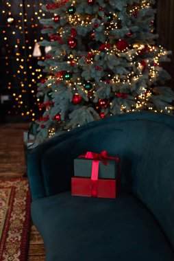 Hediye kutuları koyu mavi kadife koltukta, Noel ağacının yanında..