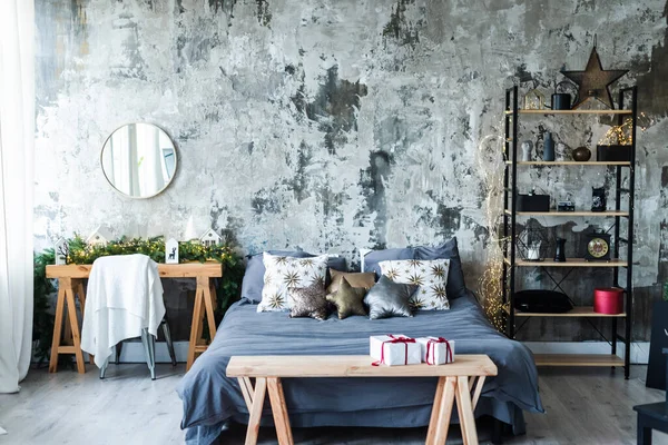 A bedroom with a double bed in gray shades with Christmas decor, a metal black shelf with things and a round makeup mirror