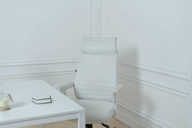 Beyaz bir ofis odası, bir sandalye ve boş beyaz bir duvarın yanında bir masa..