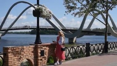 Nehir kıyısında yürüyüş yapan kırmızı elbiseli genç bir kadın.