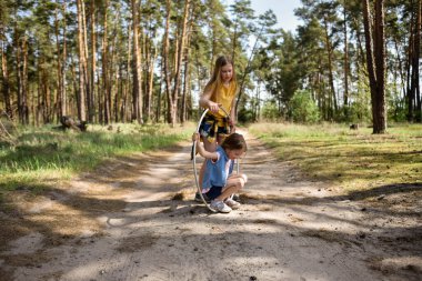Okul çağındaki tatlı kızlar ormanda bir patikada jimnastik metal bir çemberle oynuyorlar.