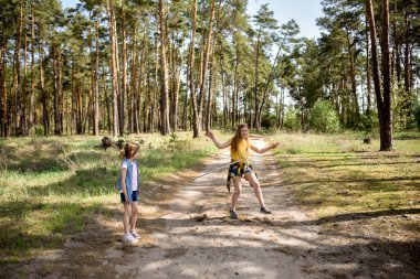 Okul çağındaki tatlı kızlar ormanda bir patikada jimnastik metal bir çemberle oynuyorlar.