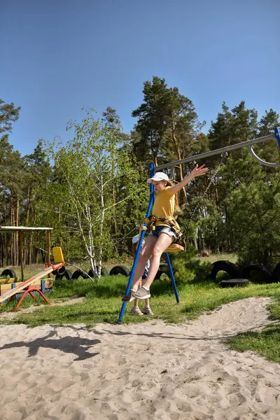İki sarışın liseli kız salıncakta sallanıyor bir çocuk parkında çam ormanının yakınında