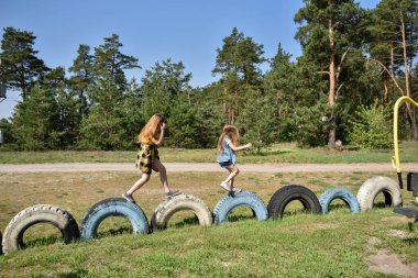 Okul çağındaki çocuklar şehir dışındaki bir çam ormanının yakınındaki bir oyun alanında oynuyorlar. Yaz tatili