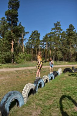 Okul çağındaki çocuklar şehir dışındaki bir çam ormanının yakınındaki bir oyun alanında oynuyorlar. Yaz tatili