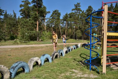 Okul çağındaki çocuklar şehir dışındaki bir çam ormanının yakınındaki bir oyun alanında oynuyorlar. Yaz tatili