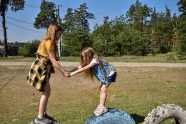 Okul çağındaki çocuklar şehir dışındaki bir çam ormanının yakınındaki bir oyun alanında oynuyorlar. Yaz tatili