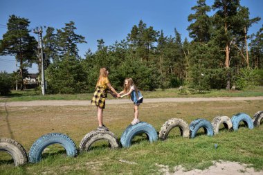 Okul çağındaki çocuklar şehir dışındaki bir çam ormanının yakınındaki bir oyun alanında oynuyorlar. Yaz tatili