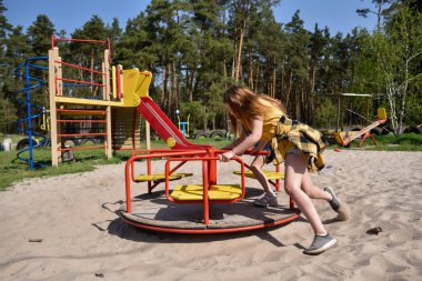 Okul çağındaki çocuklar şehir dışındaki bir çam ormanının yakınındaki bir oyun alanında oynuyorlar. Yaz tatili