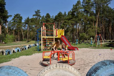 Okul çağındaki çocuklar şehir dışındaki bir çam ormanının yakınındaki bir oyun alanında oynuyorlar. Yaz tatili