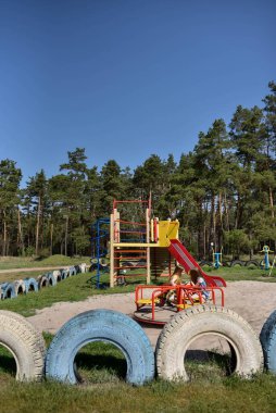 Okul çağındaki çocuklar şehir dışındaki bir çam ormanının yakınındaki bir oyun alanında oynuyorlar. Yaz tatili