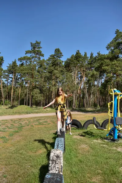 Okul çağındaki çocuklar şehir dışındaki bir çam ormanının yakınındaki bir oyun alanında oynuyorlar. Yaz tatili