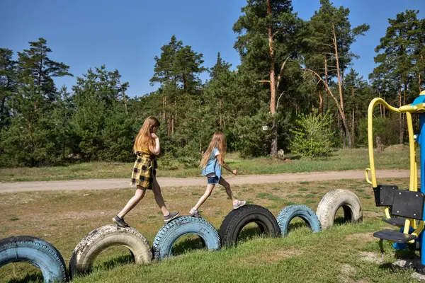 Okul çağındaki çocuklar şehir dışındaki bir çam ormanının yakınındaki bir oyun alanında oynuyorlar. Yaz tatili