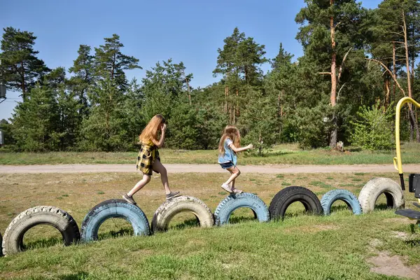 Okul çağındaki çocuklar şehir dışındaki bir çam ormanının yakınındaki bir oyun alanında oynuyorlar. Yaz tatili