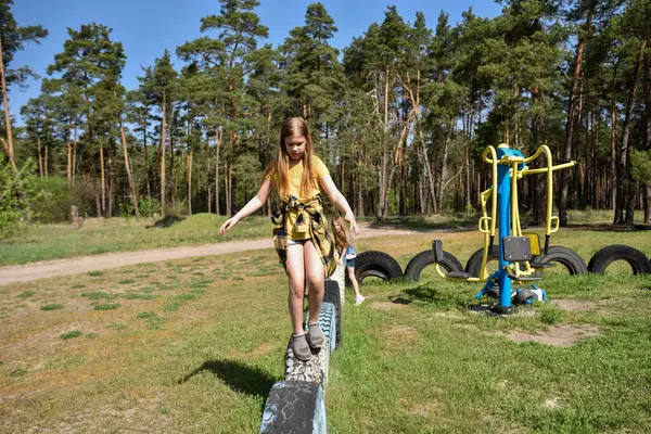 Okul çağındaki çocuklar şehir dışındaki bir çam ormanının yakınındaki bir oyun alanında oynuyorlar. Yaz tatili