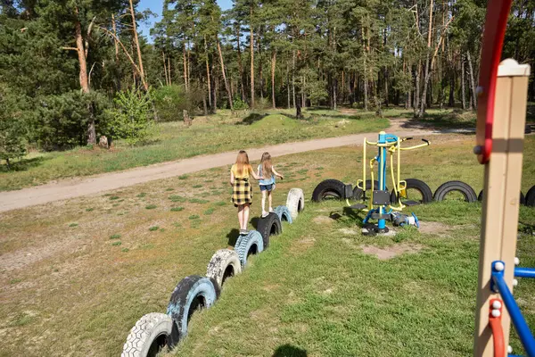 Okul çağındaki çocuklar şehir dışındaki bir çam ormanının yakınındaki bir oyun alanında oynuyorlar. Yaz tatili