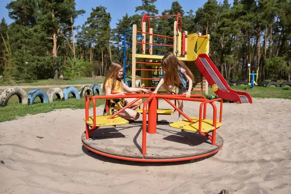 Okul çağındaki çocuklar şehir dışındaki bir çam ormanının yakınındaki bir oyun alanında oynuyorlar. Yaz tatili