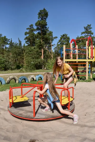 Okul çağındaki çocuklar şehir dışındaki bir çam ormanının yakınındaki bir oyun alanında oynuyorlar. Yaz tatili