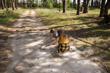 Çam ormanında bir yolda oynayan iki okul çağındaki kız.