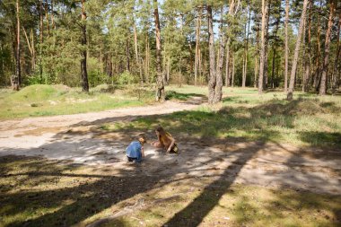 Çam ormanında bir yolda oynayan iki okul çağındaki kız.