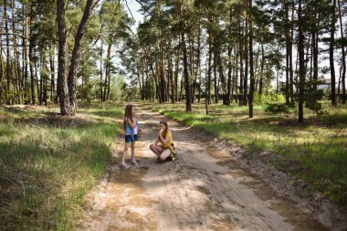 Çam ormanında yürürken dondurma yiyen iki liseli kız.