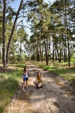 Çam ormanında yürürken dondurma yiyen iki liseli kız.