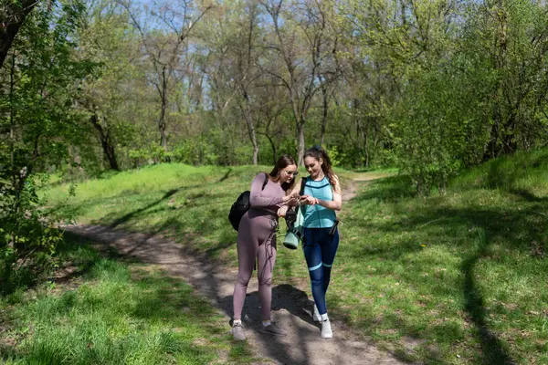 Eşofmanlı iki bayan arkadaş parkta spor yapmak için buluştular.