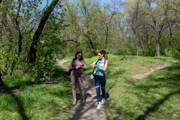 Eşofmanlı iki bayan arkadaş parkta spor yapmak için buluştular.