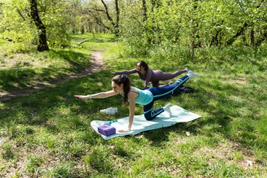 Parktaki minderlerde yoga yapan iki genç kız arkadaş.